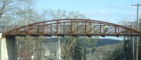 A bicyclist glides across the bike path bridge that spans over  Route 6. 