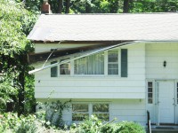 Part of a gutter hangs off one of the homes on Highland Drive damaged by falling trees last week.