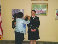 Mary Wheeler pins badge on shoulder of daughter Army Captain Dorothy Trimmer.