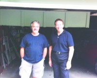 Franco Quergues, left, master carpenter and member of The Home Guru’s “EMS” group of suppliers, surveys the damage on the garage door. 