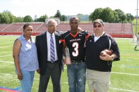 White Plains High School’s 2013 Art Monk Scholarship Award winner, senior Ari Shamery dons his number-eight Tigers jersey and holds the trophy presented to him. Shamery is pictured with (l-r) his mother Cynthia Haggins, Monks longtime friend and former Principal at WPHS Dan Woodard and Tigers Head Football Coach Skip Stevens. Photo by Al Coqueran