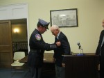 Michael Cindrich, son of the Mount Kisco mayor, awards a retirement shield from the Westchester County parkway police to John Hvisch at the Oct. 21 village board meeting.