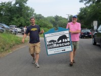 Volunteers carry the new Pet Rescue sign out to Harrison Avenue on Sunday during the open house for the new facility