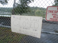 OLYMPUS DIGITAL CAMERA | The Examiner News A sign at Tonetta Lake indicates the beach is closed until further notice. The county’s health department made the call after green algae was discovered.