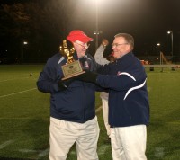 Stepinac Head Football Coach Mike O’Donnell (left) is presented the Michael Cunnion Memorial Trophy by CHSFL President Chris Hardardt for the Crusaders winning the 2014 CHSFL AAA Championship, at Fordham University, on Saturday. 