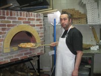 Yorktown resident Bill Ulutas, owner of Grandma’s 202 Kitchen in Yorktown, takes out a pizza from his new wood fired oven. Photo credit: Neal Rentz 