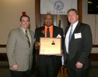 Sports-2 | The Examiner News White Plains Head Coach Spencer Mayfield (center) displays his New York State Basketball Hall of Fame Plaque presented to him by Basketball Coaches Association of New York (BCANY) President Chris Russo (left) and Vice President Todd Rose, at the Glens Falls Civic Center, on Sunday.