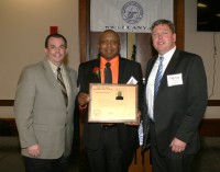 White Plains Head Coach Spencer Mayfield (center) displays his New York State Basketball Hall of Fame Plaque presented to him by Basketball Coaches Association of New York (BCANY) President Chris Russo (left) and Vice President Todd Rose, at the Glens Falls Civic Center, on Sunday. 