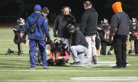 A scary point of the game was when Dr. Louis McIntyer (knelling right) and Tigers Trainer Mike Mirabella (second left) came on the field to minister to Tigers star running back Glenmour Osborne. But Osborne left the field on his feet with an elbow injury and is reported to be doing fine. 