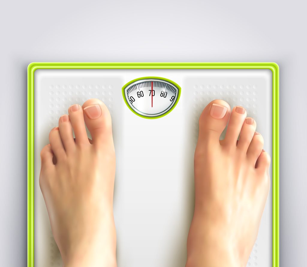 analog bathroom scales - white floor scale with a lime green background. Two feet are seen on the scale.