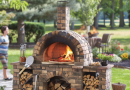 Outdoor pizza oven setup in a backyard with pizza tools and people socializing around. pizza oven safety