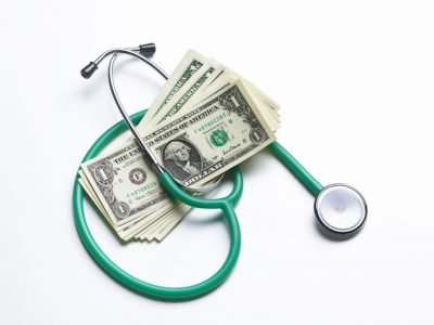 Stethoscope with US dollar notes to represent cost of insurance