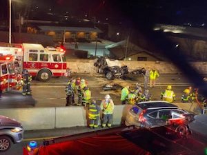 Firefighters standing at the scene of a fatal car crash