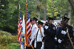 Service men and police officers holding American flags at a 9/11 memorial ceremony