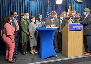 County Executive George Latimer, surrounded by Westchester officials and representatives from an assortment of advisory boards, signs the Anti-Discrimination Harassment Bill that broadens protections for residents who are subjected to certain offenses.